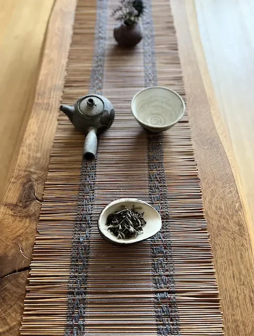 Bambus Chabu auf einem Teetisch aus Eiche gedeckt mit Teeschalen und Teeblättern